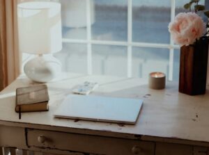 How to reset your life when everything feels too much. Image shows a window with a desk in front of it, with an open notebook
