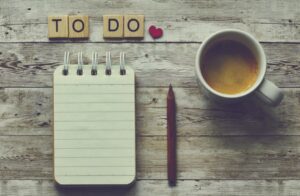 Why you still feel overwhelmed even though you’re trying your best. Image shows a desk with a notebook, pen and cup, and letter tiles reading ‘to do’ 