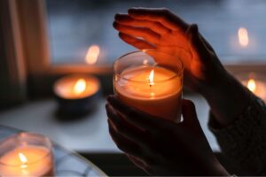 Habits that improve mental clarity. Image shows a lit candle in evening light, with a hand protecting the flame 