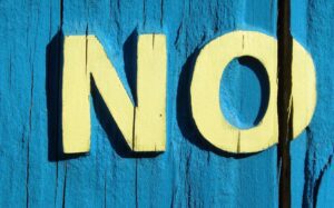 Habits that improve mental clarity. Image shows painted lettering on blue wood background, reading ‘NO’