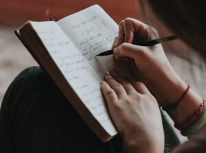 What to write in a journal. Image shows a journal with hands writing in it 