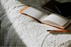 What to write in a journal. Image shows an open notebook on a bed 