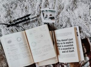Journaling styles. Image shows a journal with writing in, next to a several Polaroid photographs and an open book showing a quote in large text