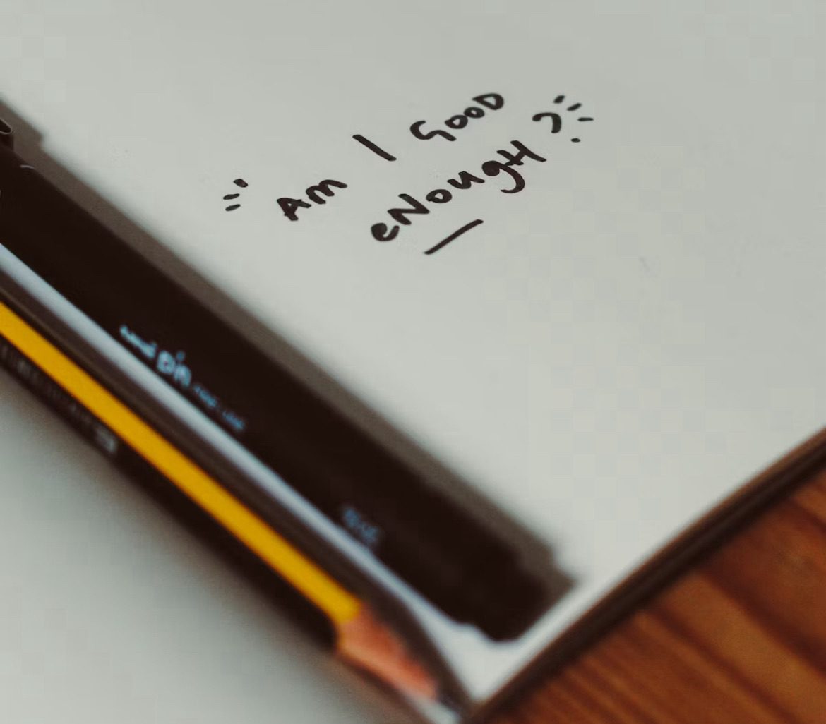 Journaling for anxiety. Image shows a notebook with ‘am I good enough?’ Written on it 