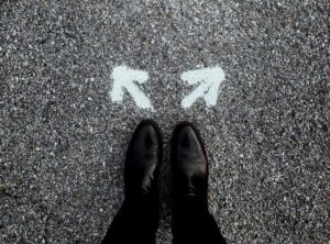 Journaling to make a decision. Image shows feet standing still behind two white arrows painted on the road, pointing in different directions 
