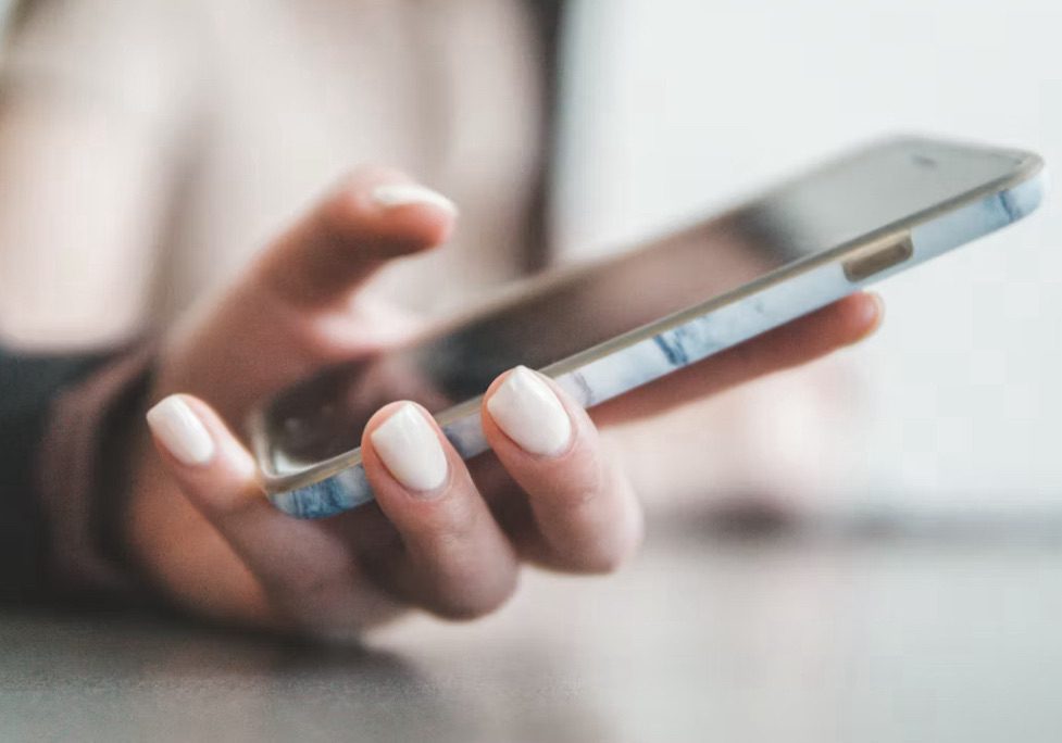 Image shows a hand holding a mobile phone 