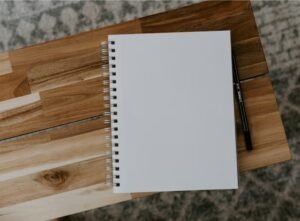 Image shows a blank notebook on a wooden chopping board