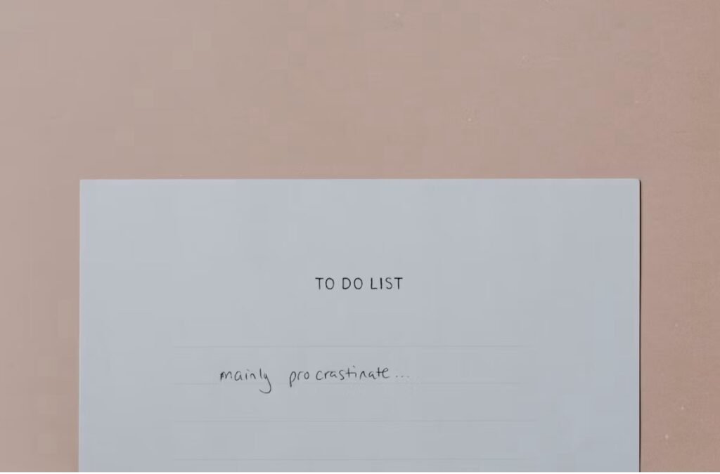 Why am I procrastinating? Images shows a piece of paper with writing reading ‘To Do List: Mostly procrastinate’ 