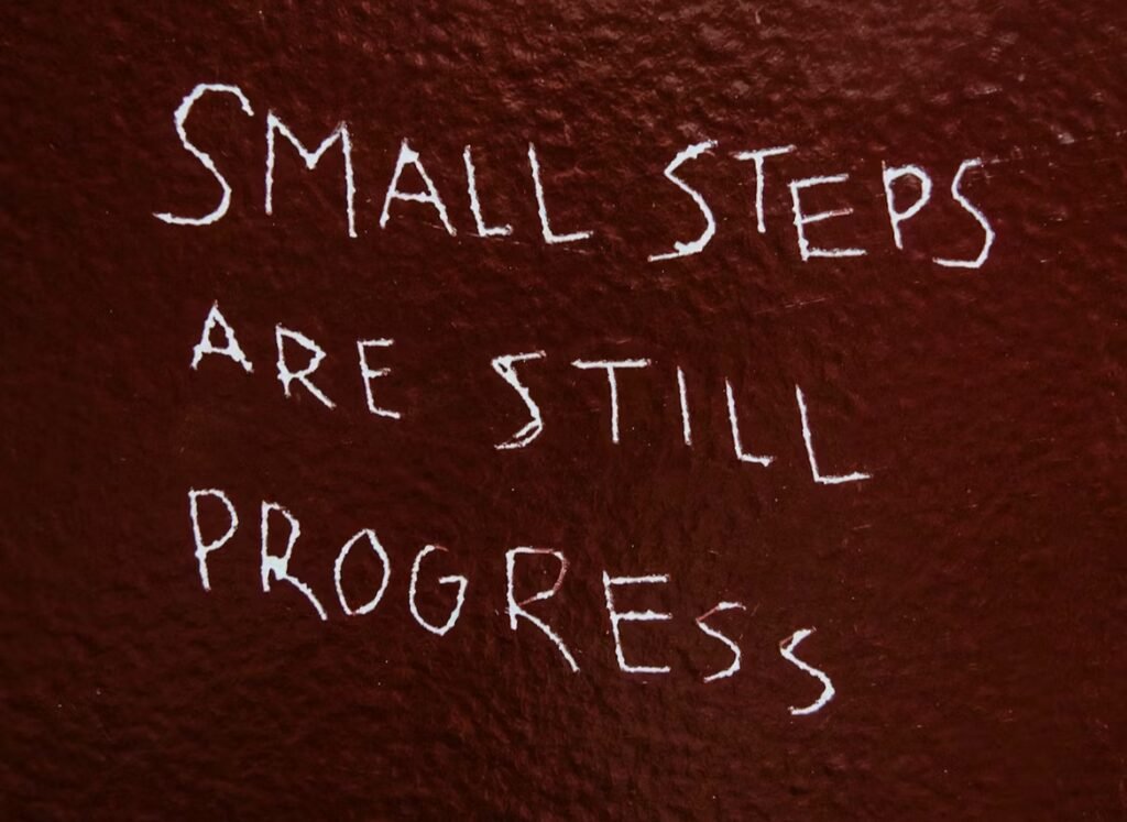 Why am I procrastinating? Image shows a blackboard with writing that reads ‘small steps are still progress’ 